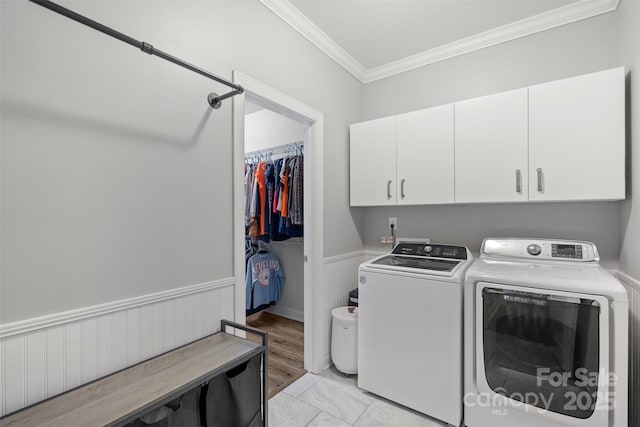 clothes washing area featuring ornamental molding, cabinets, light tile patterned flooring, and washing machine and clothes dryer