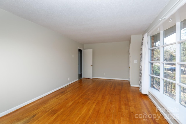 spare room with a textured ceiling and hardwood / wood-style flooring