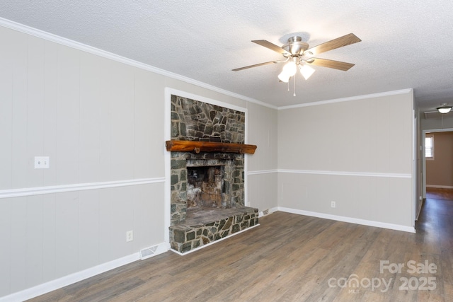 unfurnished living room featuring a stone fireplace, crown molding, ceiling fan, a textured ceiling, and dark hardwood / wood-style flooring