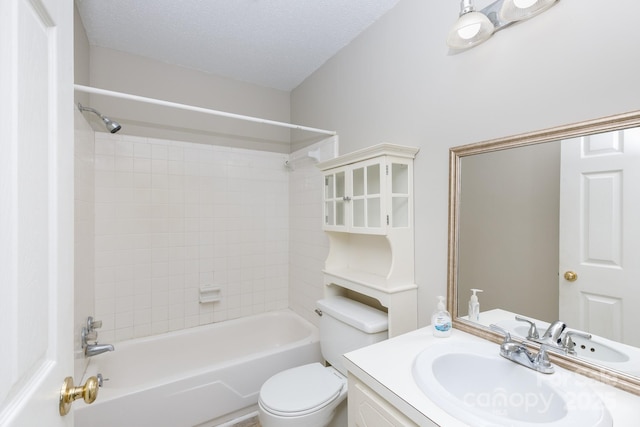 full bathroom with vanity, toilet, a textured ceiling, and tiled shower / bath combo