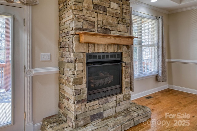 room details with a stone fireplace, ornamental molding, and hardwood / wood-style floors