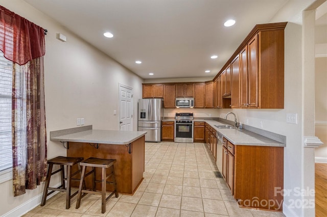 kitchen featuring kitchen peninsula, a kitchen breakfast bar, sink, light tile patterned floors, and stainless steel appliances