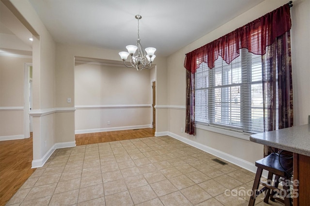 unfurnished dining area with tile patterned flooring and a notable chandelier