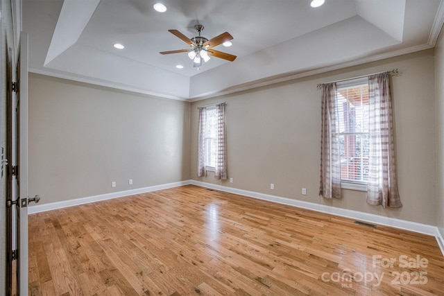 unfurnished room with a healthy amount of sunlight, light hardwood / wood-style floors, and a tray ceiling