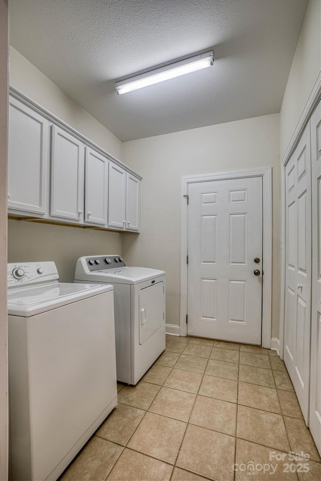 laundry area featuring light tile patterned flooring, a textured ceiling, cabinets, and independent washer and dryer