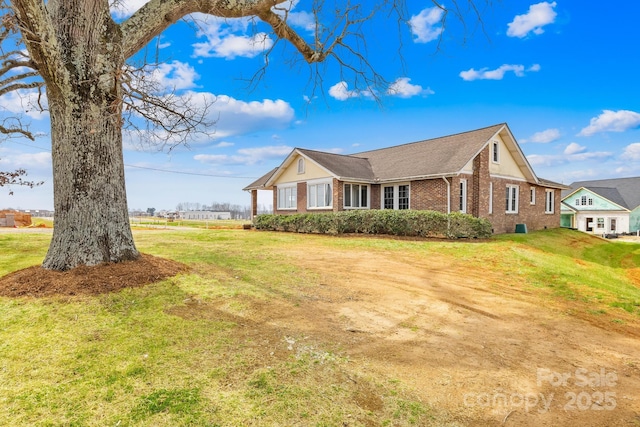 view of front of property with a front lawn, brick siding, and roof with shingles