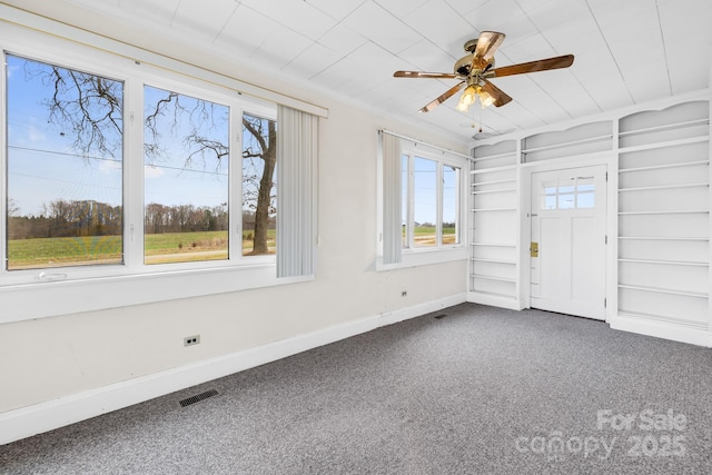 interior space featuring visible vents, a ceiling fan, baseboards, and ornamental molding