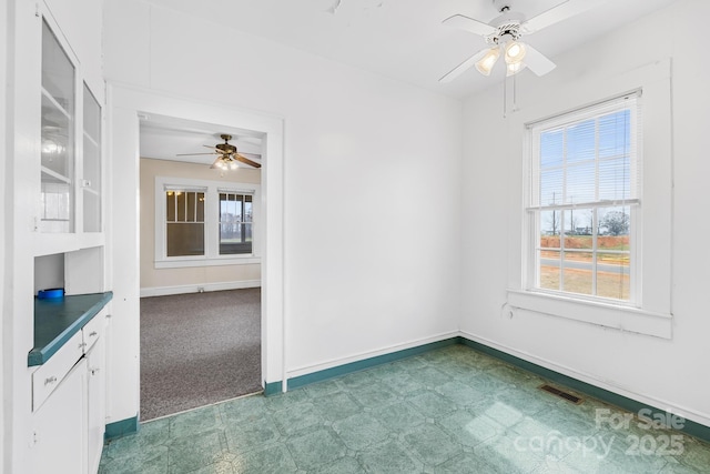 carpeted spare room with tile patterned floors, baseboards, visible vents, and ceiling fan