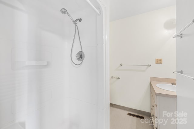 bathroom with vanity, a shower, visible vents, and baseboards