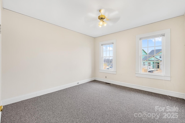 carpeted empty room featuring visible vents, ceiling fan, and baseboards