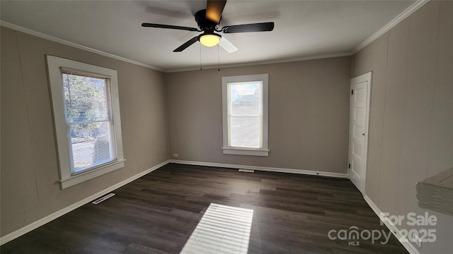 spare room with crown molding, ceiling fan, dark hardwood / wood-style flooring, and a healthy amount of sunlight