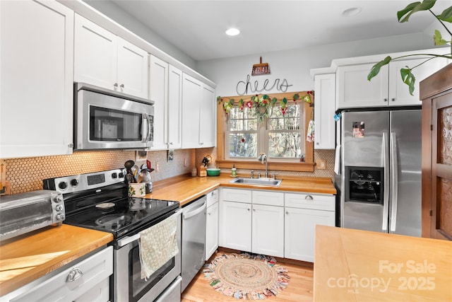 kitchen featuring white cabinets, butcher block countertops, sink, and stainless steel appliances