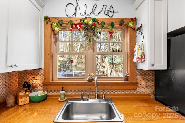 kitchen featuring white cabinets, backsplash, and sink