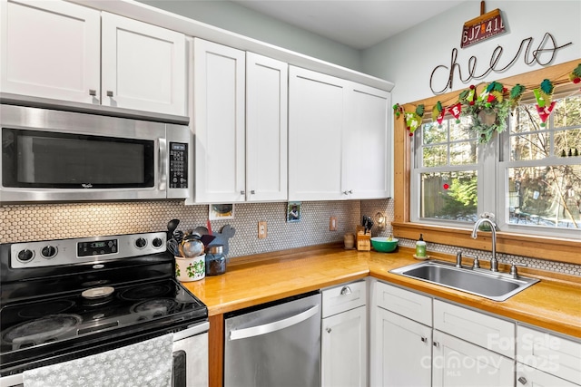 kitchen with white cabinets, butcher block counters, stainless steel appliances, decorative backsplash, and sink