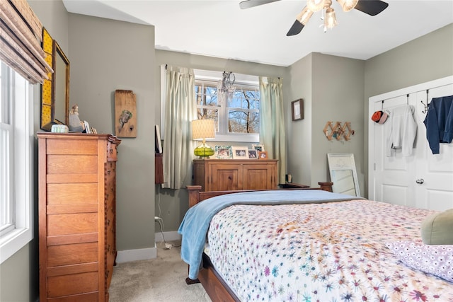 carpeted bedroom with ceiling fan, a closet, and multiple windows