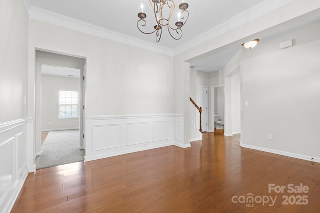 empty room featuring hardwood / wood-style flooring, ornamental molding, and a chandelier