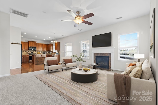 living room featuring a high end fireplace and ceiling fan with notable chandelier