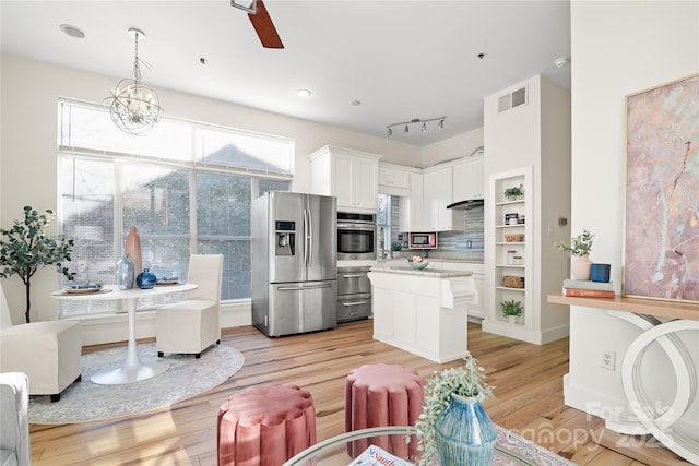 kitchen featuring tasteful backsplash, pendant lighting, light hardwood / wood-style flooring, white cabinets, and stainless steel fridge