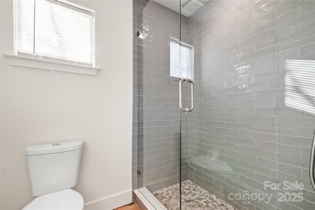 bathroom featuring toilet and a shower with shower door