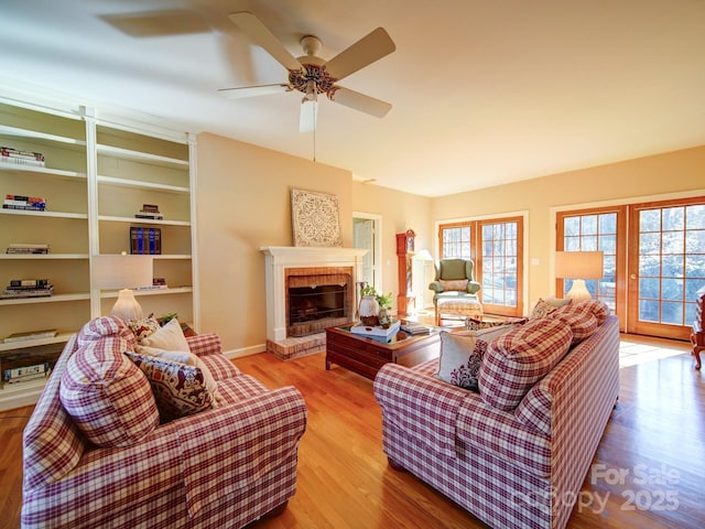 living room featuring light wood-type flooring, a brick fireplace, and ceiling fan