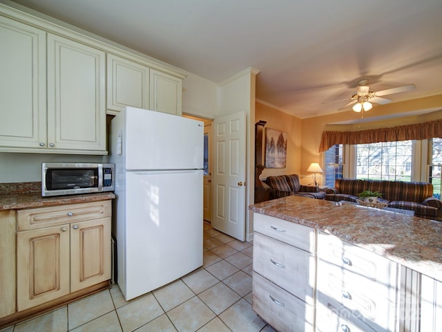 kitchen with ceiling fan, light stone counters, white fridge, cream cabinetry, and light tile patterned floors