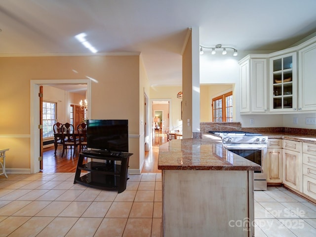 kitchen featuring range with electric stovetop, dark stone countertops, kitchen peninsula, light tile patterned floors, and ornamental molding