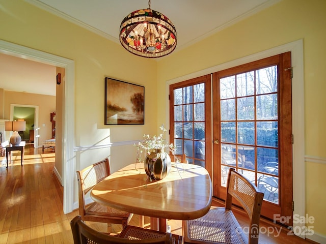 dining space featuring french doors, light hardwood / wood-style flooring, ornamental molding, and a notable chandelier