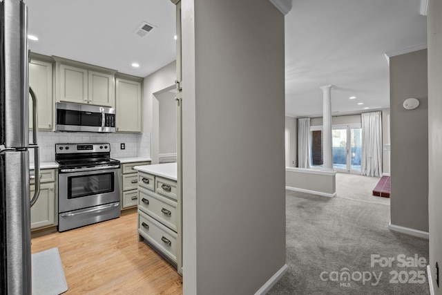 kitchen with appliances with stainless steel finishes, light carpet, tasteful backsplash, and decorative columns