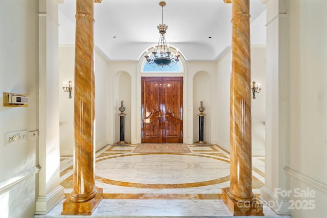 foyer entrance featuring an inviting chandelier and ornate columns