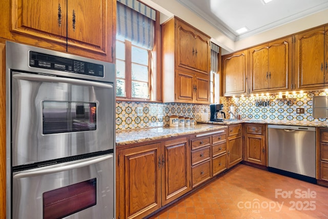 kitchen featuring appliances with stainless steel finishes, decorative backsplash, ornamental molding, light tile patterned floors, and light stone countertops