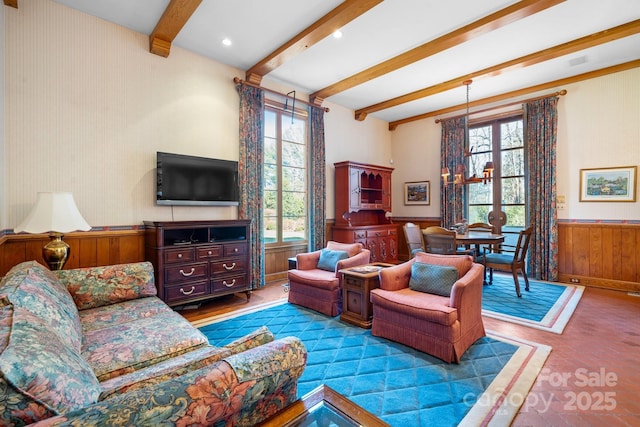 living room featuring beam ceiling, plenty of natural light, and wooden walls