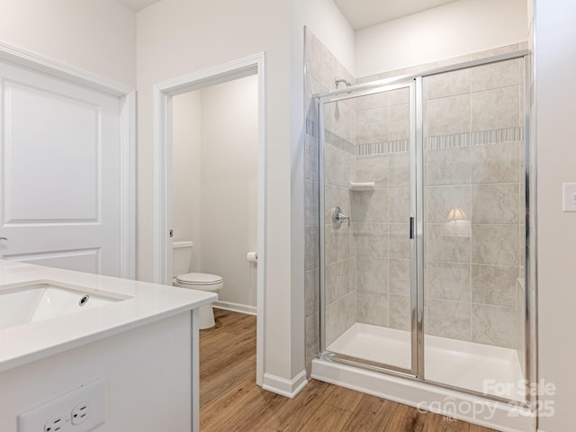 bathroom featuring toilet, hardwood / wood-style flooring, an enclosed shower, and vanity