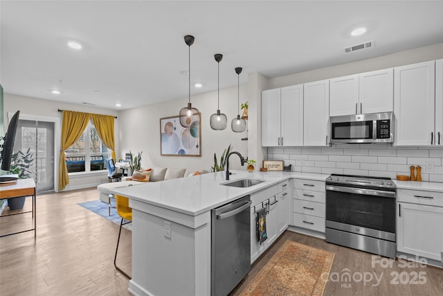 kitchen with stainless steel appliances, white cabinetry, and kitchen peninsula