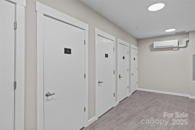 hall with an AC wall unit and light hardwood / wood-style floors