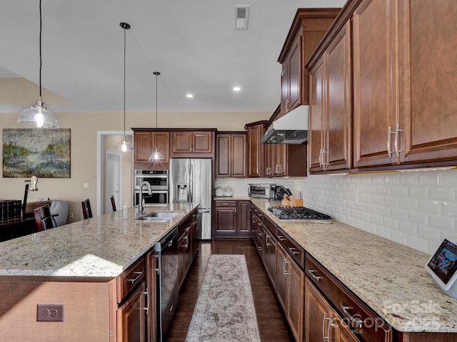 kitchen featuring decorative light fixtures, a spacious island, sink, stainless steel appliances, and light stone counters