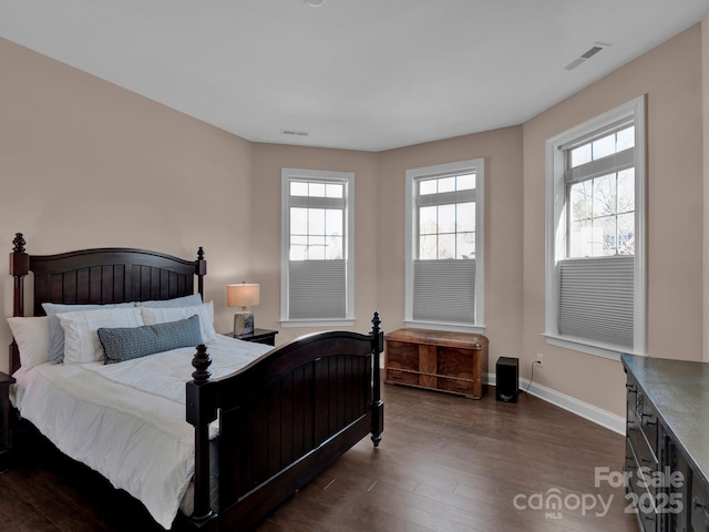 bedroom with dark hardwood / wood-style floors and multiple windows