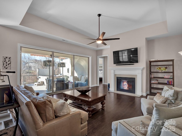 living room featuring a raised ceiling, ceiling fan, and dark hardwood / wood-style floors