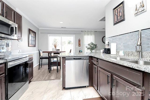 kitchen with kitchen peninsula, sink, appliances with stainless steel finishes, light stone counters, and dark brown cabinetry