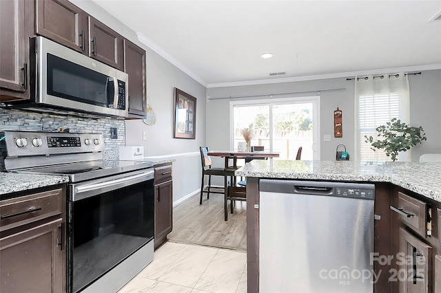 kitchen with light stone countertops, tasteful backsplash, ornamental molding, dark brown cabinets, and stainless steel appliances