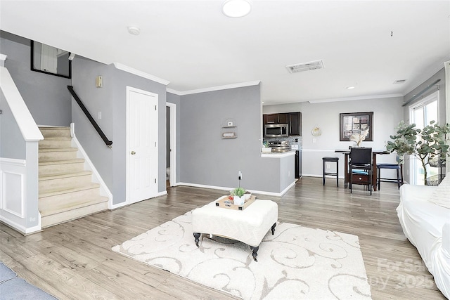 living room featuring crown molding and light hardwood / wood-style flooring