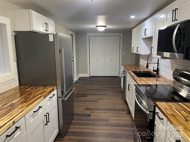 kitchen with butcher block counters, sink, white cabinets, dark hardwood / wood-style flooring, and stainless steel appliances