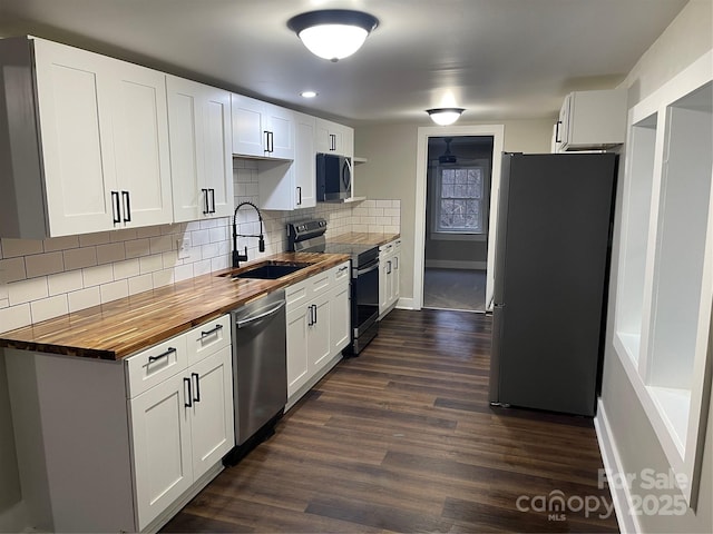 kitchen with wood counters, stainless steel appliances, sink, and white cabinets