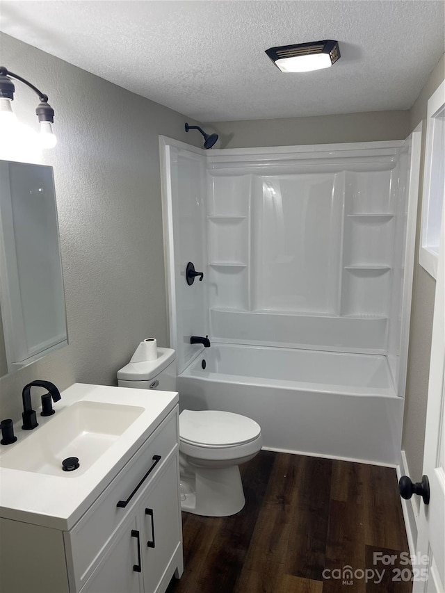 full bathroom featuring toilet, wood-type flooring,  shower combination, a textured ceiling, and vanity