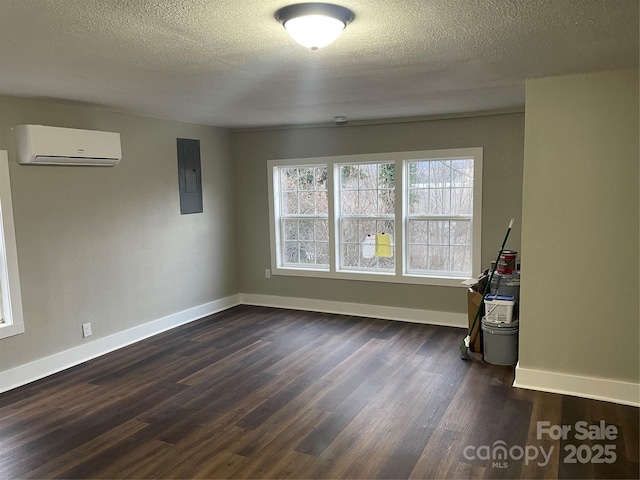 unfurnished room featuring dark wood-type flooring, a wall mounted air conditioner, electric panel, and a textured ceiling