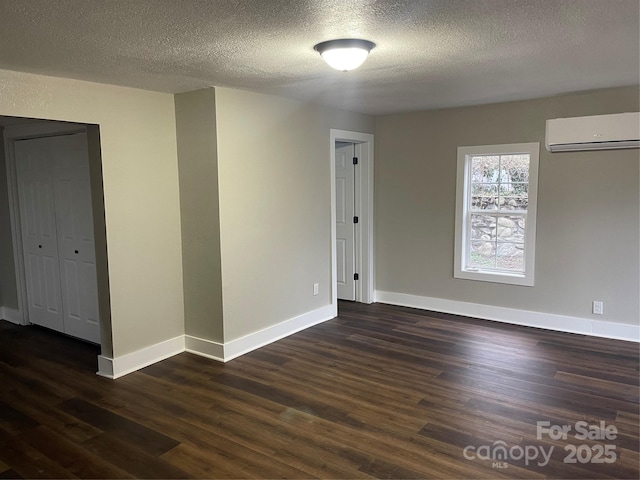 spare room with dark hardwood / wood-style flooring, a textured ceiling, and an AC wall unit