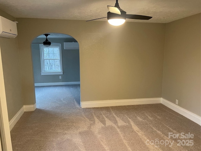 empty room featuring ceiling fan, carpet flooring, a wall mounted air conditioner, and a textured ceiling