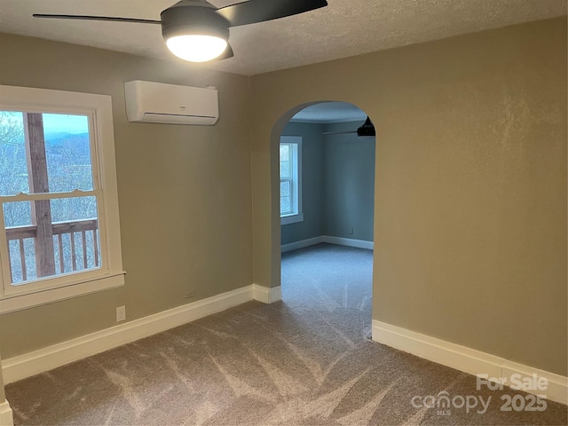 spare room featuring ceiling fan, a wall mounted air conditioner, carpet, and a textured ceiling