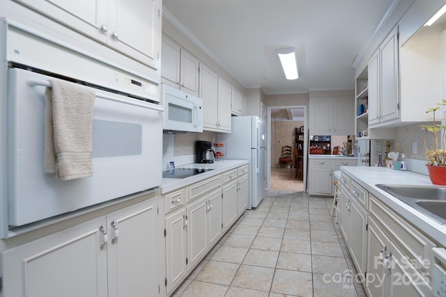 kitchen with white appliances, decorative backsplash, ornamental molding, light tile patterned floors, and white cabinetry