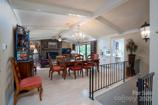 dining area with vaulted ceiling with beams, a large fireplace, ceiling fan with notable chandelier, and light wood-type flooring