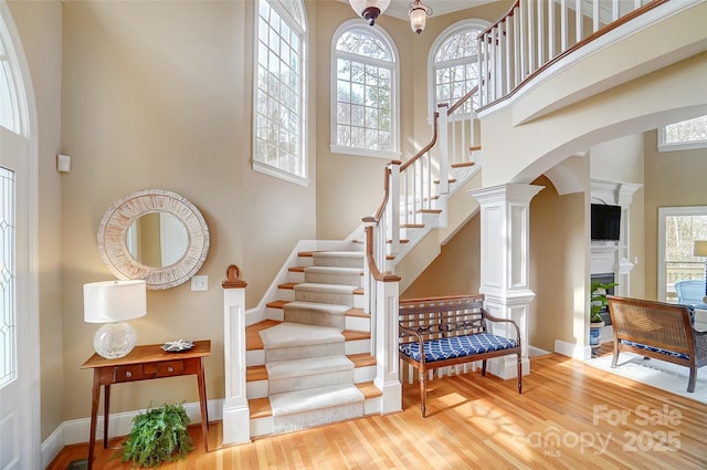 staircase with hardwood / wood-style floors and a towering ceiling